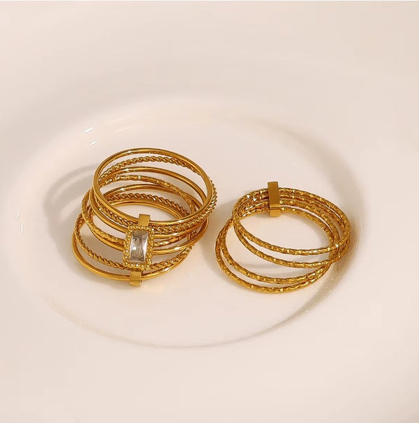 Επιχρυσωμένο ατσάλινο δαχτυλίδι με πλεκτές λεπτομέρειες και πέτρα baguette