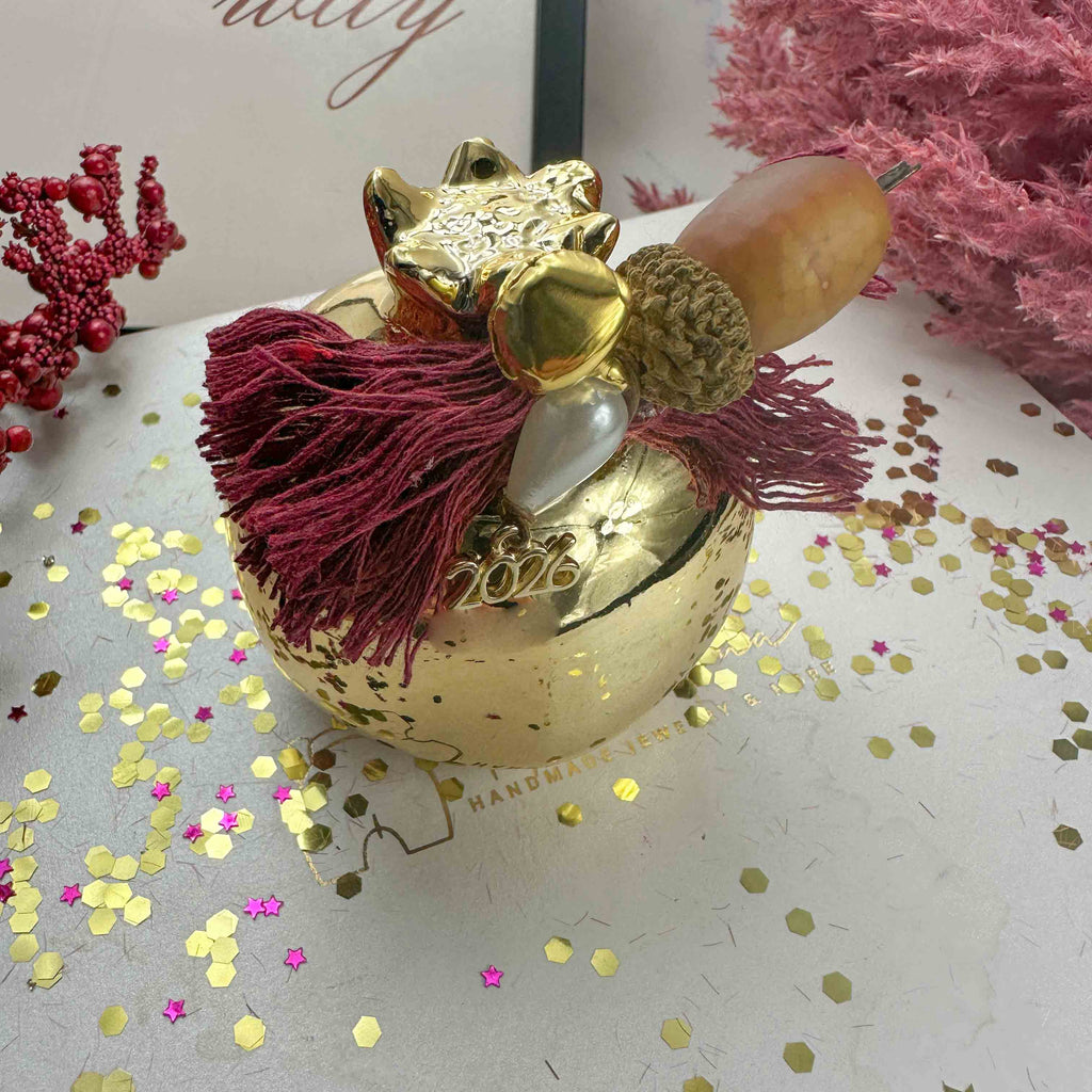 Κεραμικό Χρυσό Ρόδι Διακοσμητικό – Γούρι 2026 με Μπορντό Βαμβακερές Κλωστές (7×7cm)