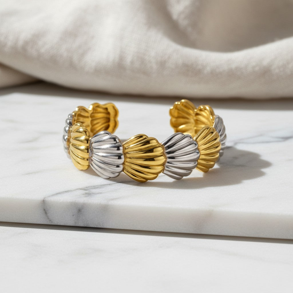 Βραχιόλι cuff elephantina.gr σε σχήμα κοχυλιών με εναλλασσόμενα χρυσά και ασημένια στοιχεία πάνω σε μάρμαρο.