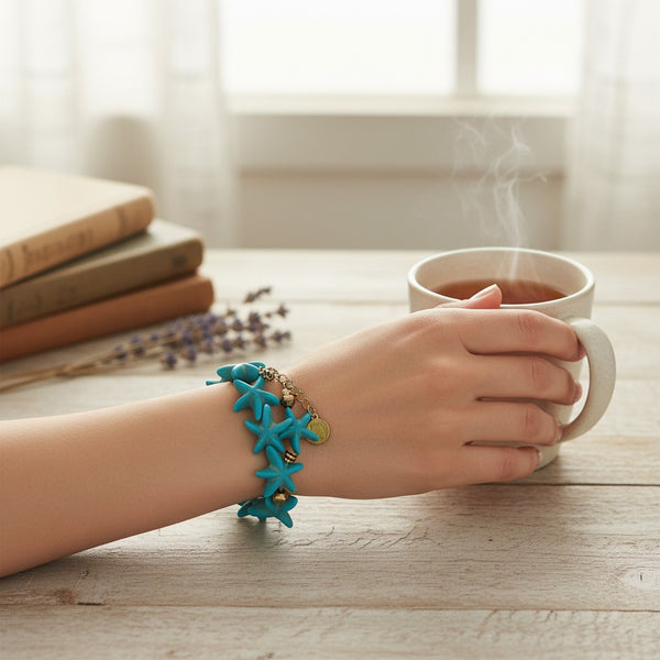 elephantina.gr Fuji bracelet featuring turquoise starfish charms and gold-tone accents worn on a wrist with tea