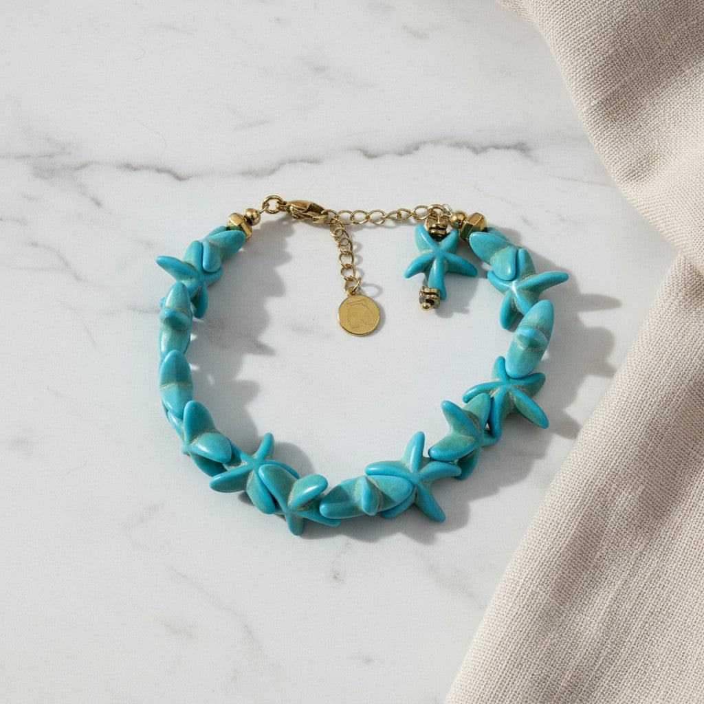 elephantina.gr Fuji bracelet featuring turquoise starfish-shaped beads with gold-tone metal accents on marble surface