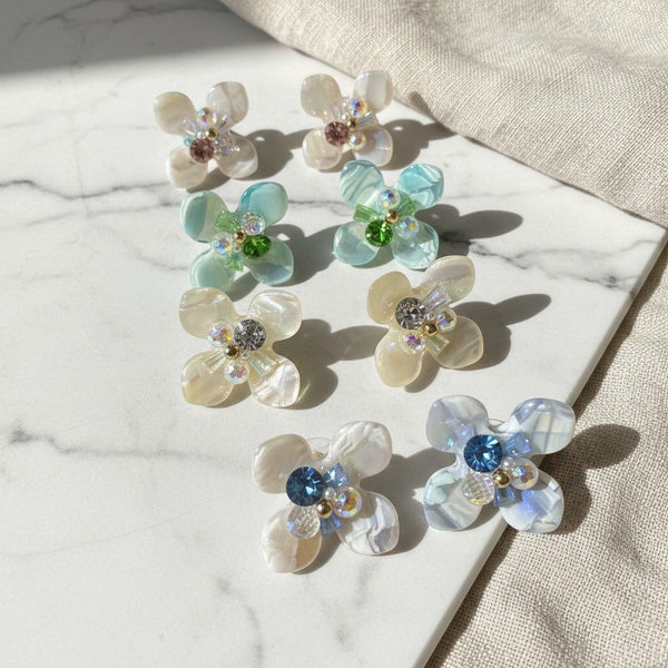 elephantina.gr flower earrings with iridescent petals and colorful crystal centers on a marble surface