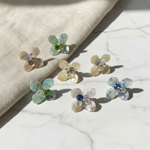 elephantina.gr flower earrings with iridescent petals and colorful crystal centers on a marble surface.