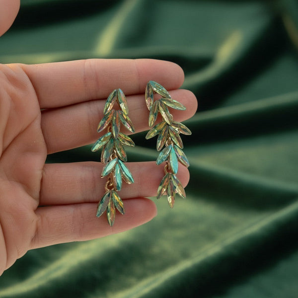 elephantina.gr dangle earrings featuring iridescent green leaf-shaped crystals held in a hand