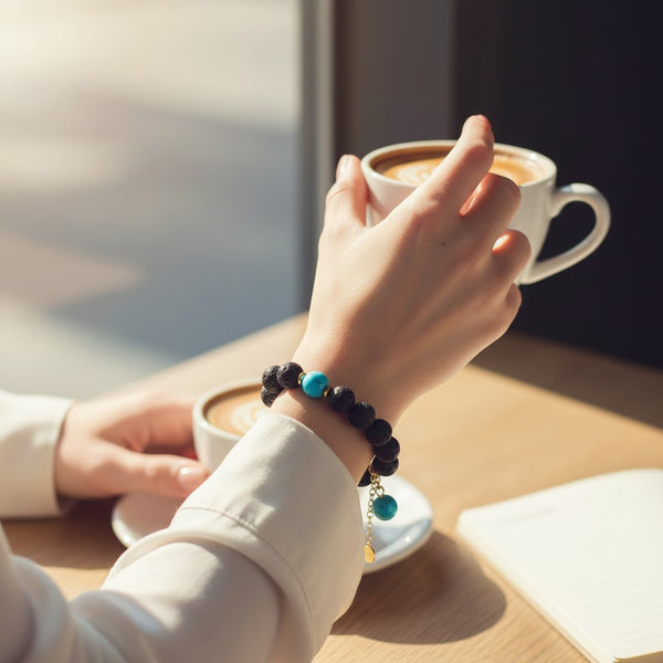elephantina.gr beaded bracelet with black lava stones and turquoise accents worn by a person holding a coffee cup