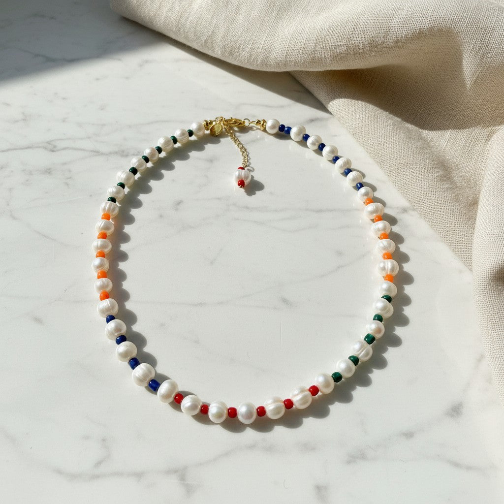 elephantina.gr necklace featuring white freshwater pearls interspersed with vibrant red, blue, orange, and green beads.