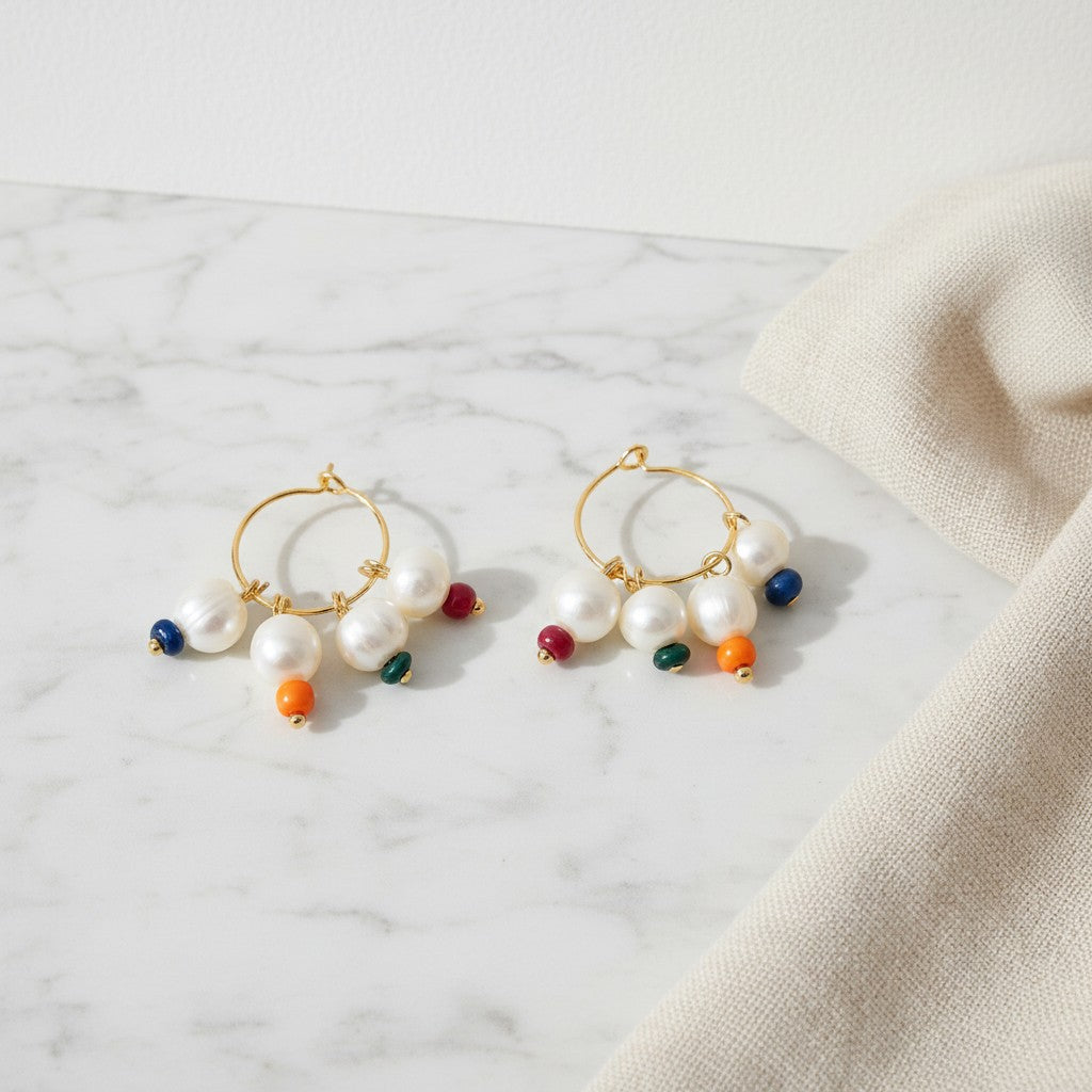 elephantina.gr gold hoop earrings featuring white freshwater pearls and small colorful accent beads on marble surface