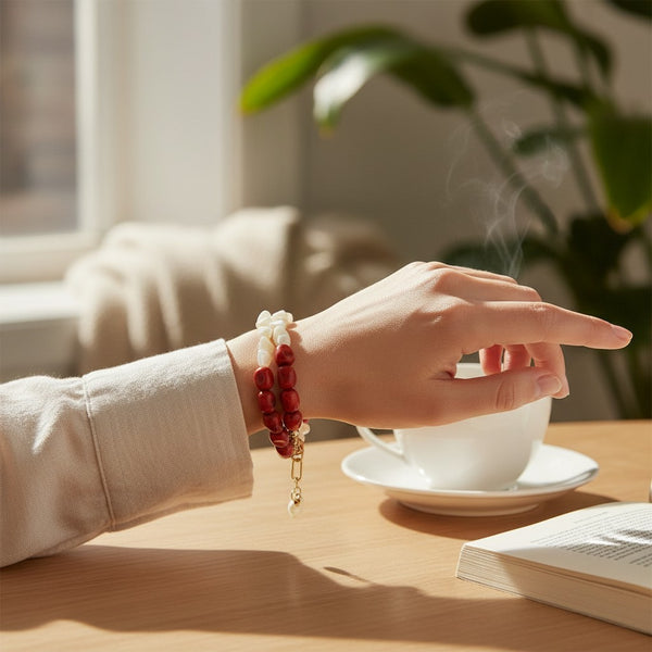elephantina.gr double-strand bracelet with red wooden beads and white pearls on a woman's wrist at a cafe table