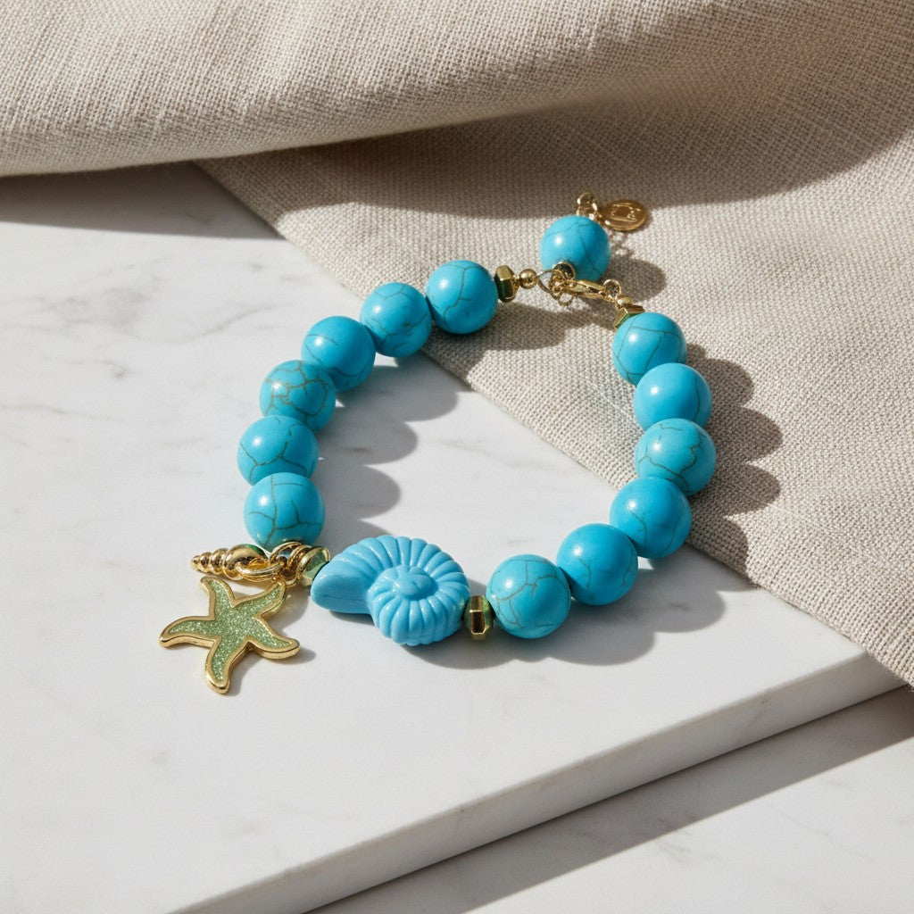 elephantina.gr HHy bracelet featuring turquoise beads, a gold starfish charm, and a seashell accent on marble