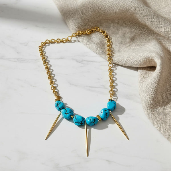 elephantina.gr necklace featuring bright blue turquoise stones and gold-tone metal spikes on a chunky chain