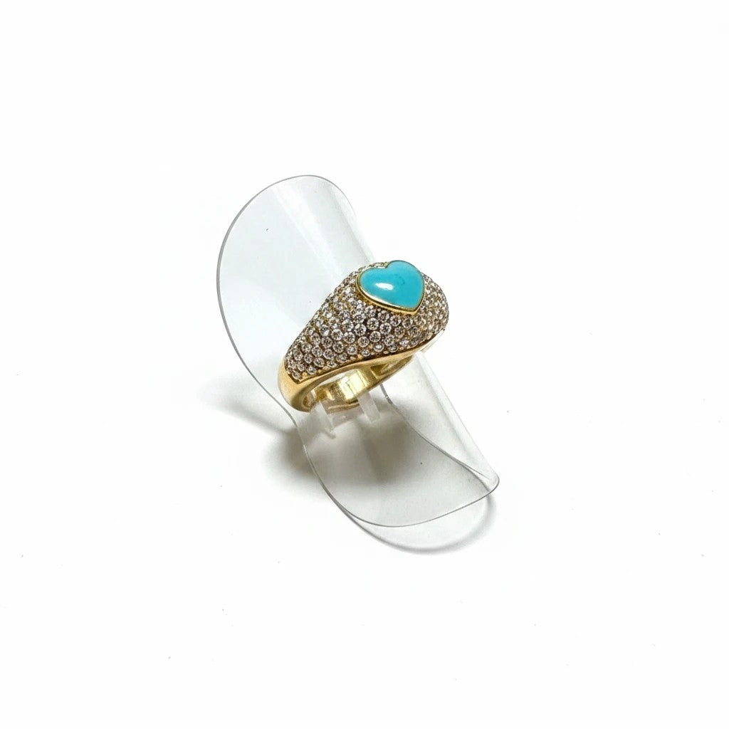 elephantina.gr gold-tone statement ring with a turquoise heart centerpiece and pavé crystal band on a clear stand.