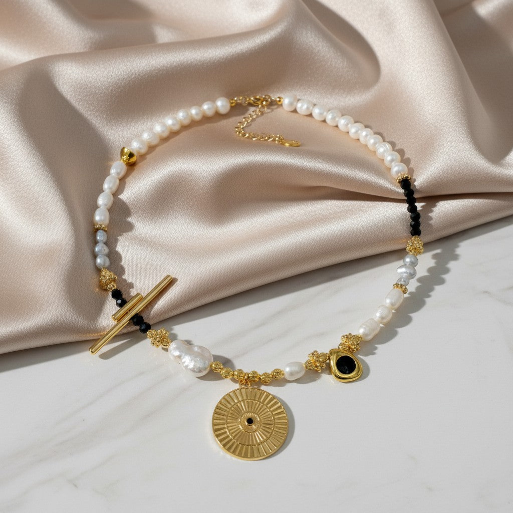 Elephantina.gr Helios Noir necklace with ivory pearls, black crystals, gold elements, and sun pendant.