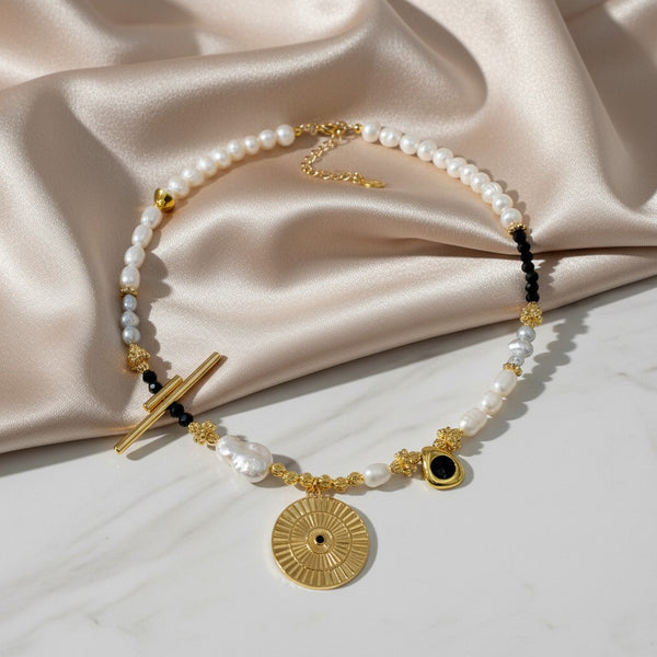 Elephantina.gr Helios Noir necklace with ivory pearls, black crystals, gold elements, and sun pendant.