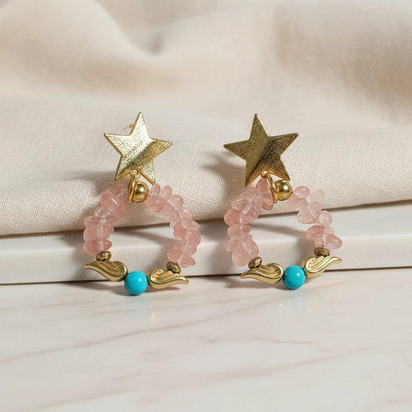 Elephantina.gr gold star hoop earrings with pink gemstones and turquoise beads. Textured gold stars dangle from hoops adorned with pink stones and turquoise beads.