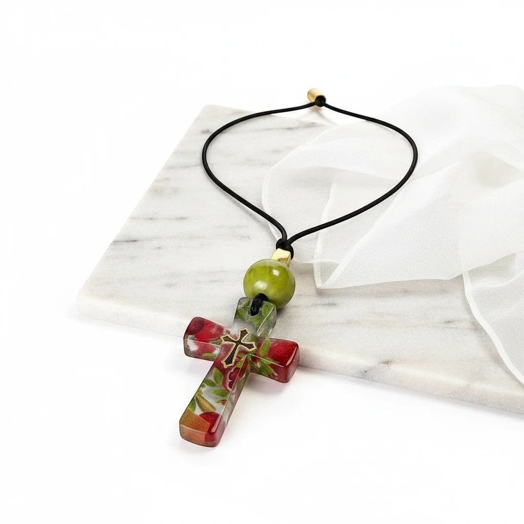 elephantina.gr resin cross pendant necklace with embedded red flowers and green leaves, on black cord with green bead.