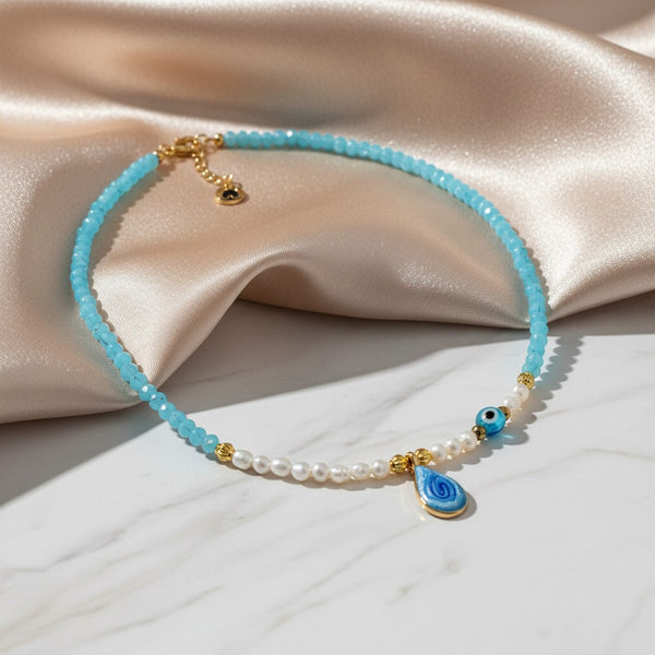elephantina.gr handmade necklace with blue drop enamel, rice pearls, and blue crystals. Features a blue evil eye charm.