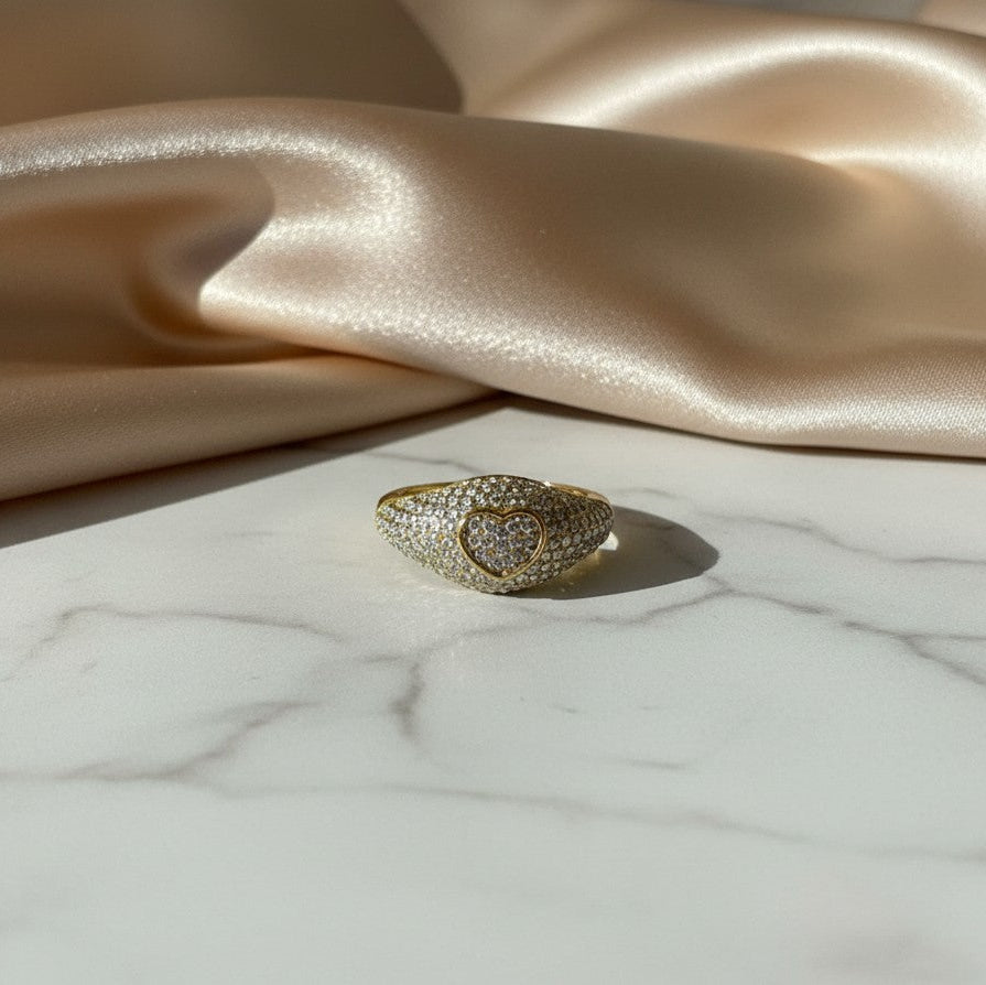 elephantina.gr gold-tone heart signet ring encrusted with shimmering crystals on a white marble and satin background