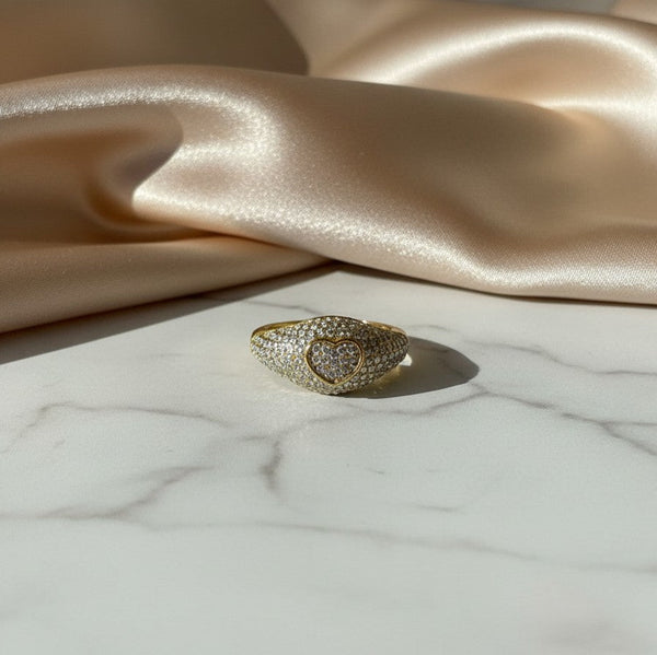 elephantina.gr gold-tone heart signet ring encrusted with shimmering crystals on a white marble and satin background
