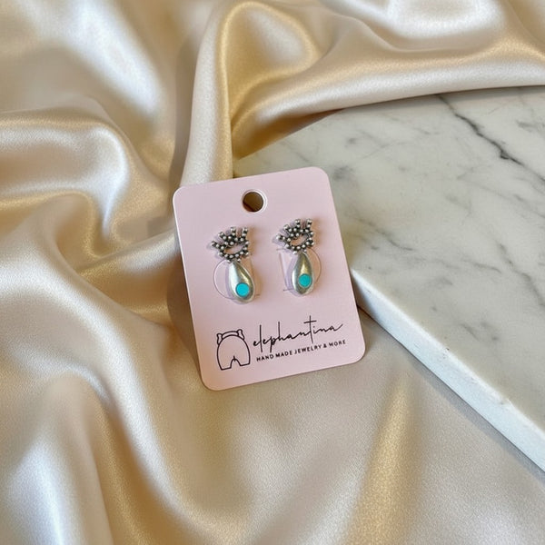 Handmade elephantina.gr silver-toned eye stud earrings with turquoise accent and crown detail.