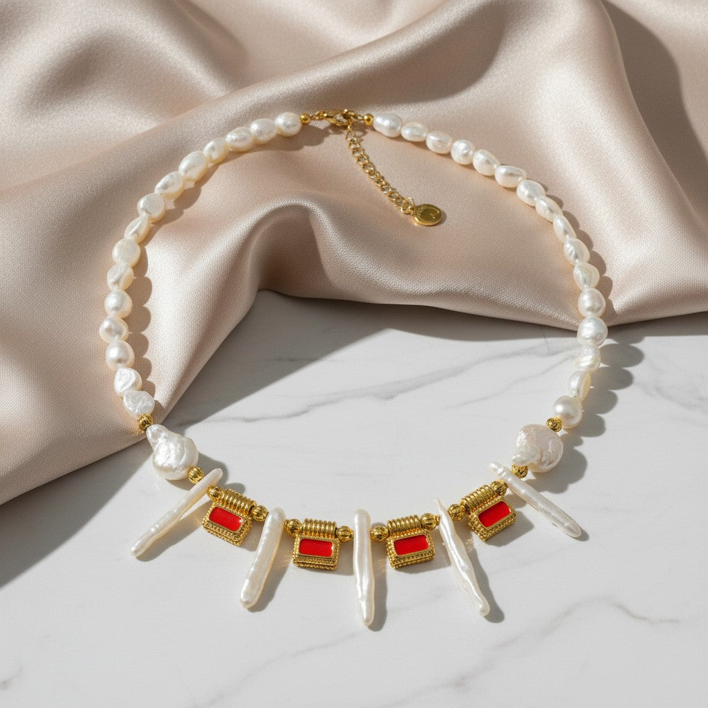 elephantina.gr necklace with Biwa pearls, baroque pearls, and gold accents with orange enamel. Features irregular pearls and geometric orange enamel rectangles.
