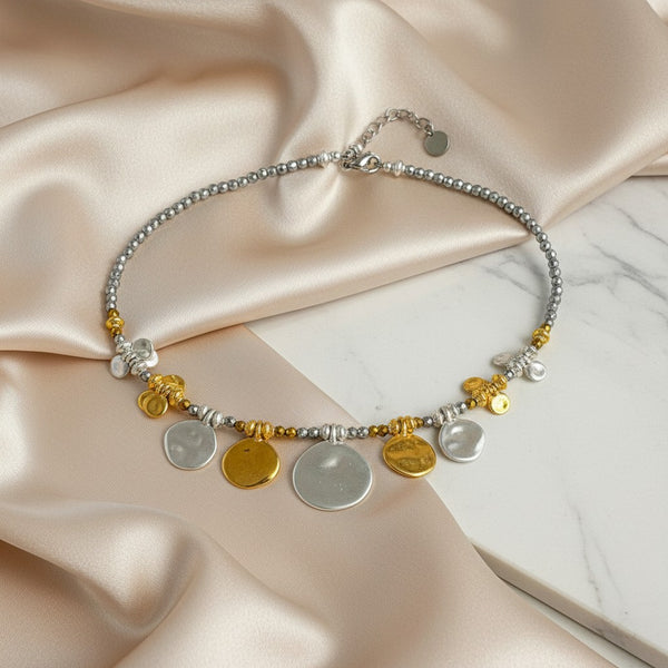 Elephantina.gr silver necklace with gold accents, featuring beaded chain and dangling hammered discs. Modern chic design.