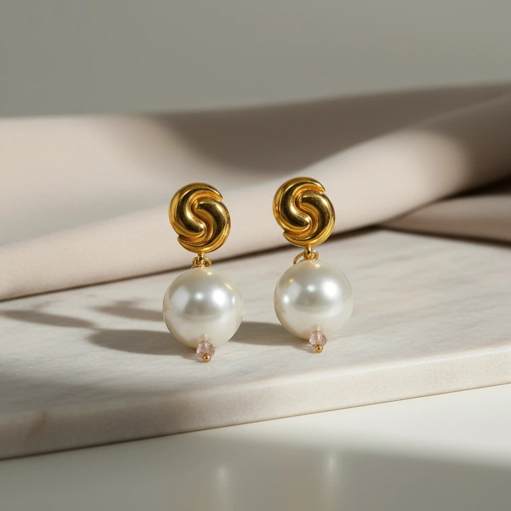 Elephantina.gr gold-tone swirl drop earrings with large grey pearls and small pink crystal accents.