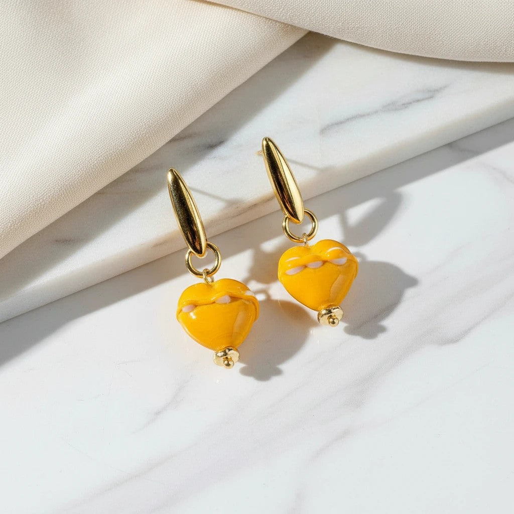 elephantina.gr handmade mustard yellow ceramic heart earrings with white enamel details and gold-tone hardware.