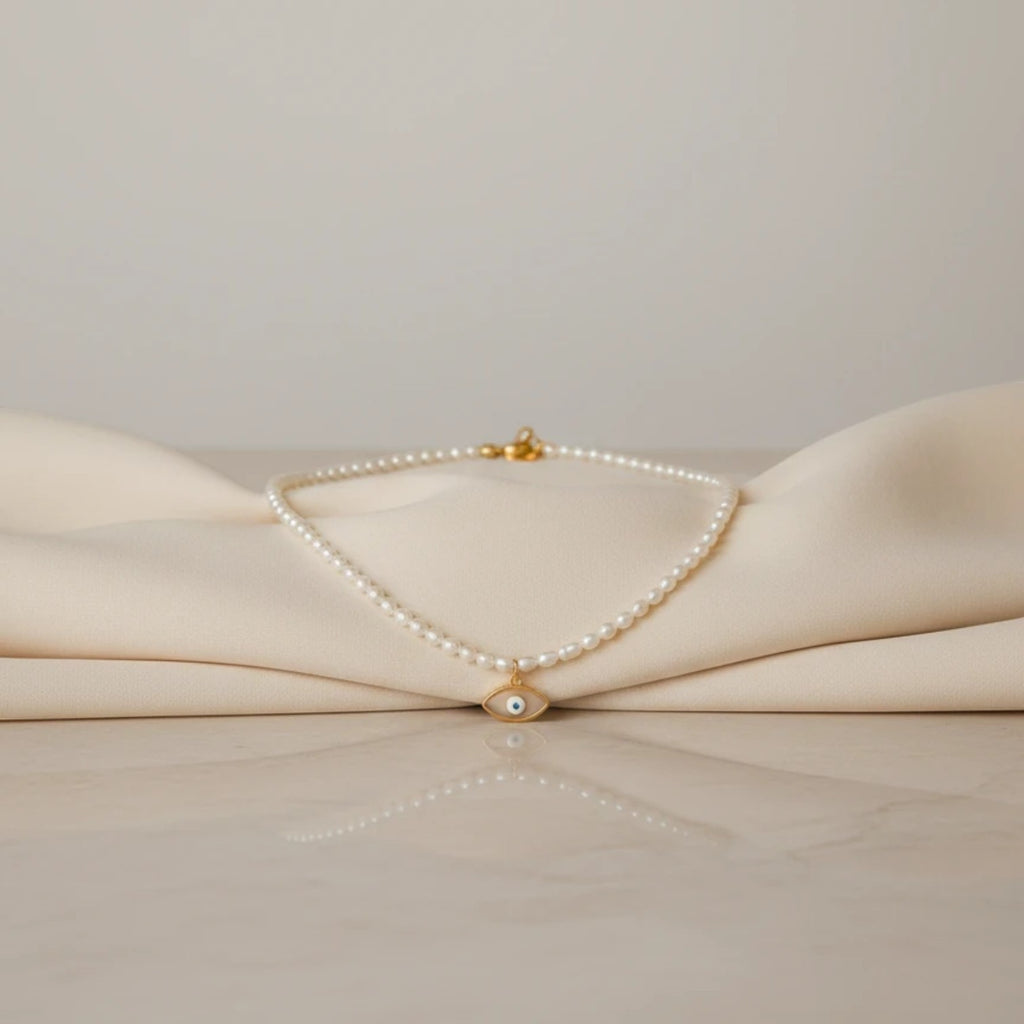 elephantina.gr necklace with small white pearls and a gold evil eye charm with blue detail. Minimalist and elegant.