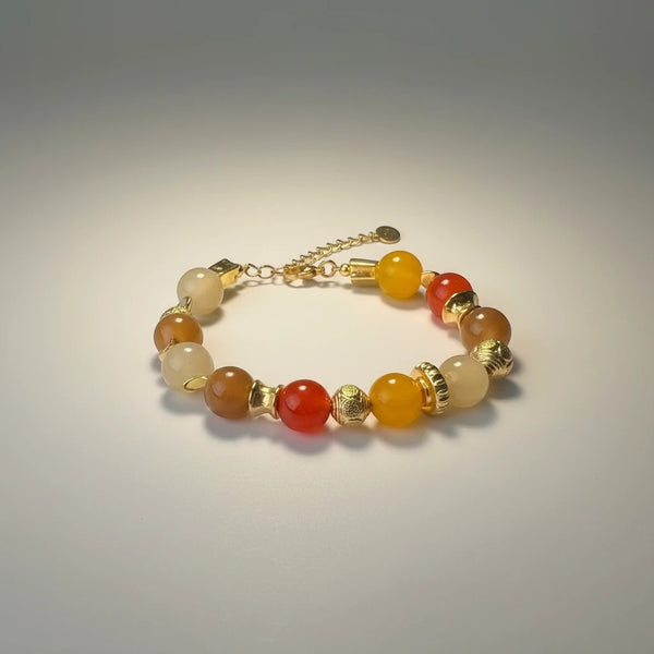 Handmade elephantina.gr bracelet with glass beads in warm orange, honey, and sand tones, accented with gold elements. Features an adjustable clasp.