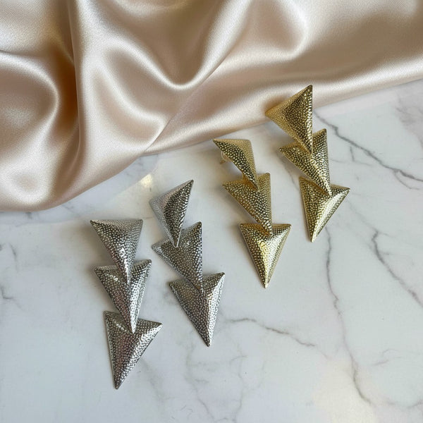 elephantina.gr gold and silver geometric triangle drop earrings with a textured finish on a marble surface.