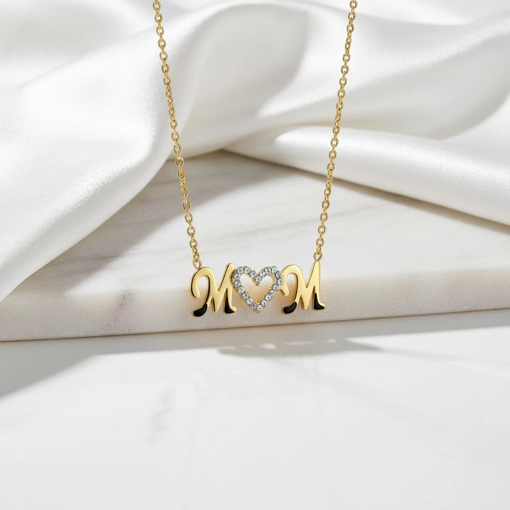 Gold-tone stainless steel necklace with "Mom" spelled out, featuring a heart with cubic zirconia between the letters. Adjustable chain.