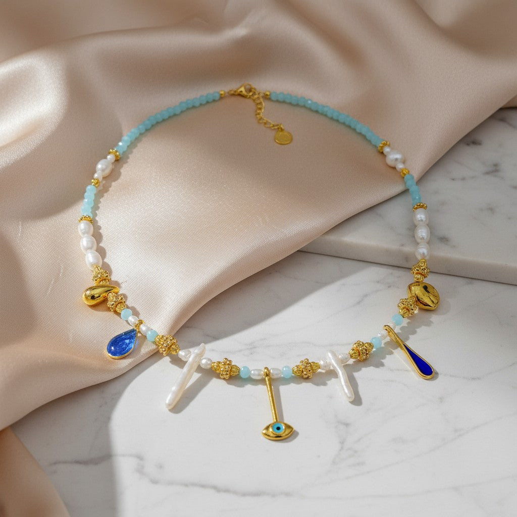 Elephantina.gr necklace with Biwa pearls, blue crystals, gold elements, and evil eye charm. Boho chic.
