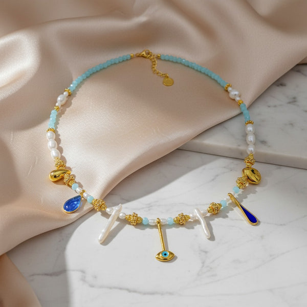 Elephantina.gr necklace with Biwa pearls, blue crystals, gold elements, and evil eye charm. Boho chic.