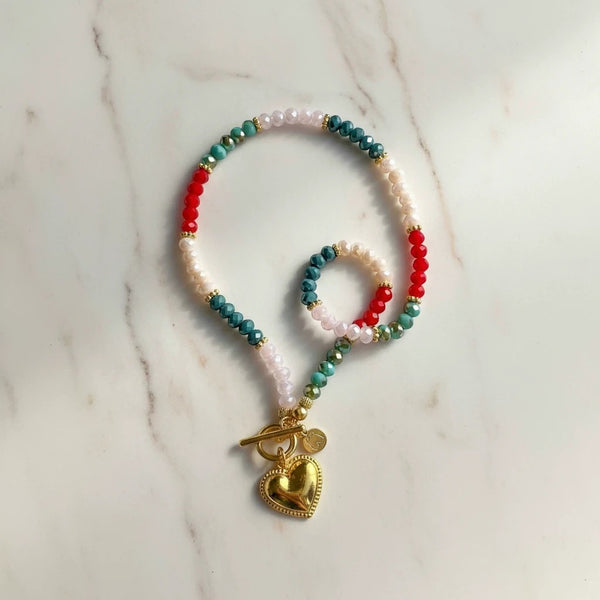 Elephantina.gr beaded necklace with colorful crystals and gold heart pendant. Features red, teal, pink, and cream beads.