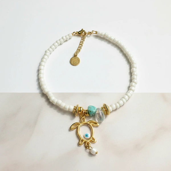 Elephantina.gr gold turtle anklet with white beads, turquoise stone, and evil eye detail.