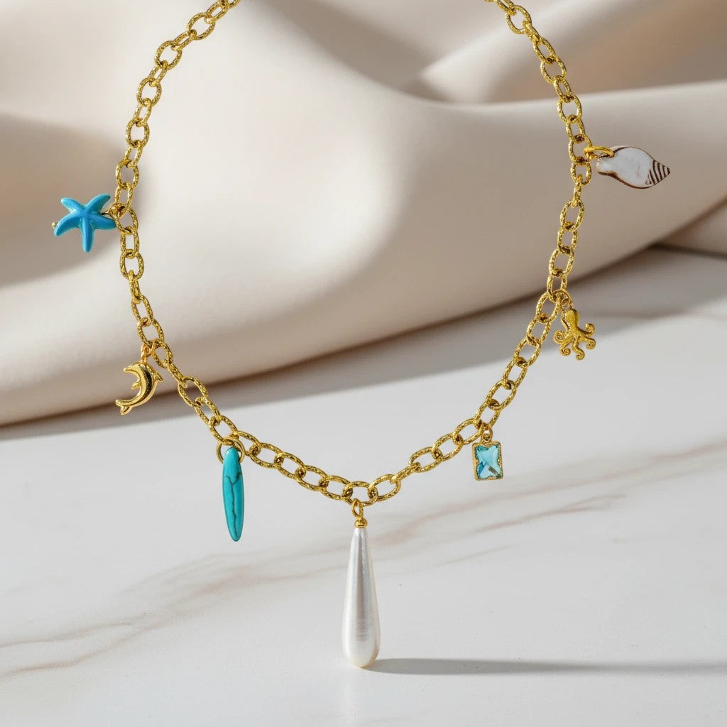 Gold chain necklace with sea charms: starfish, dolphin, surfboard, octopus, shell, and pearl drop. elephantina.gr