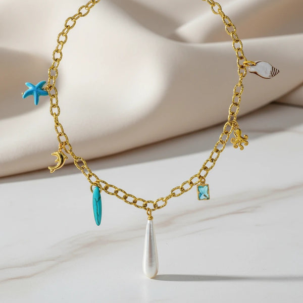 Gold chain necklace with sea charms: starfish, dolphin, surfboard, octopus, shell, and pearl drop. elephantina.gr