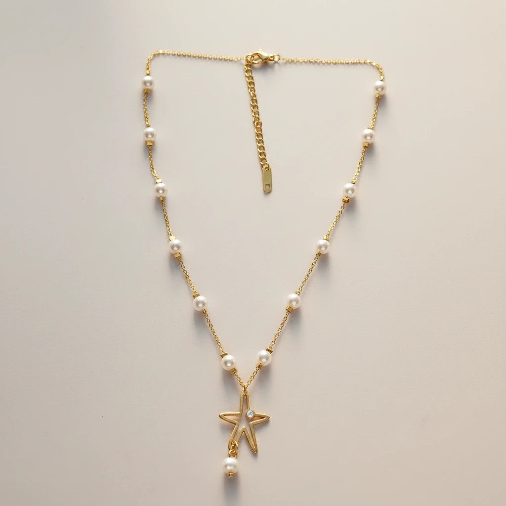Gold stainless steel necklace with white pearls and a star pendant with a pearl drop. Adjustable chain.