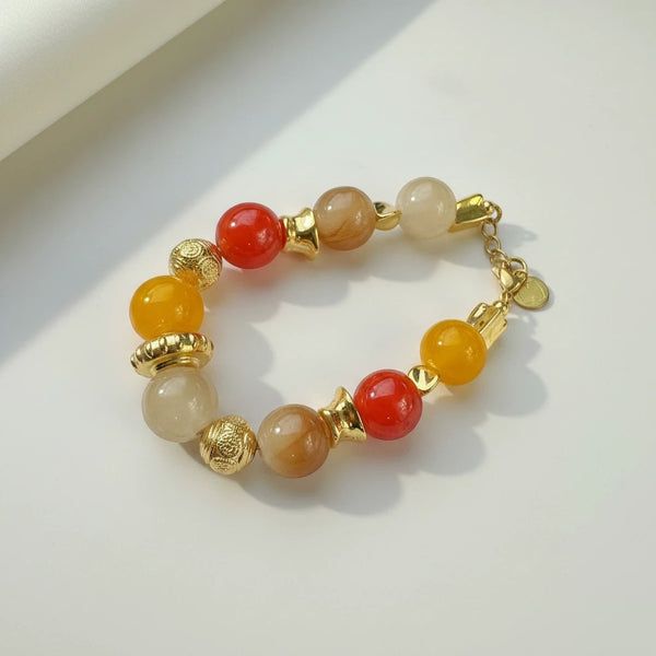 Handmade elephantina.gr bracelet with glass beads in warm orange, honey, and sand tones, accented with gold elements. Features an adjustable chain.