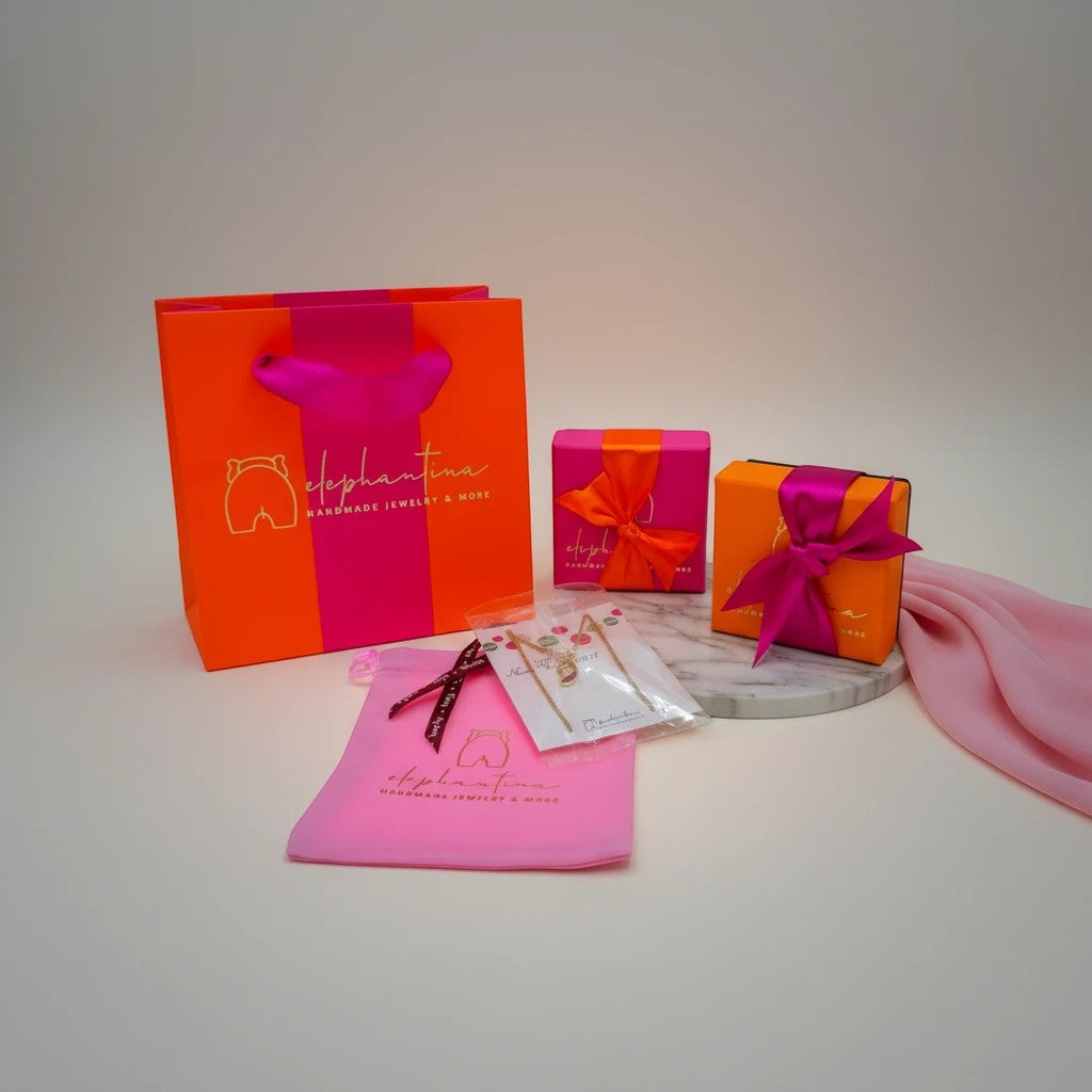 elephantina.gr gift packaging set with orange shopping bag, pink pouch, and two gift boxes with ribbon.