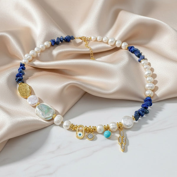 Elephantina.gr statement necklace with pearls, lapis lazuli, and gold charms. Features turquoise, white, and gold colors with evil eye and geometric motifs.