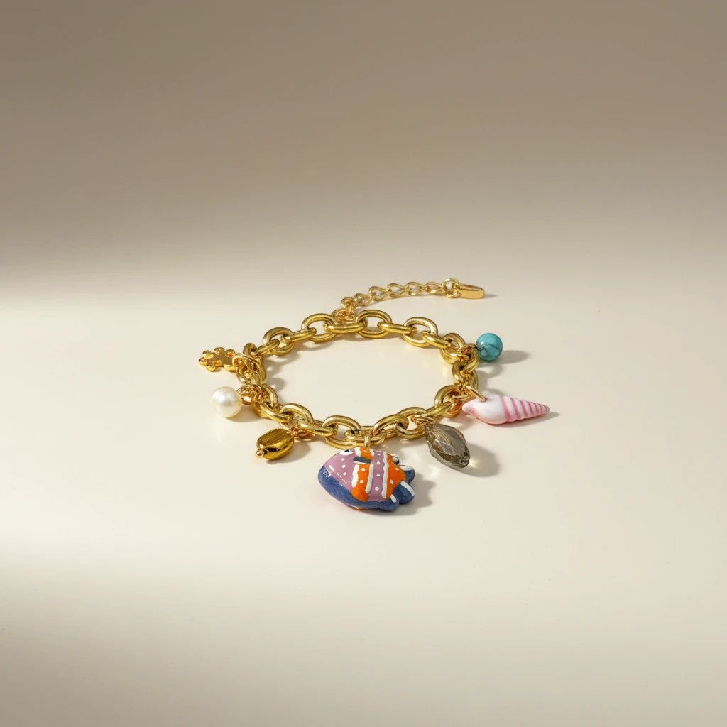 Gold chain bracelet with colorful charms: Murano glass fish, pearl, turquoise, shell, and hematite. Elephantina.gr boho summer jewelry.