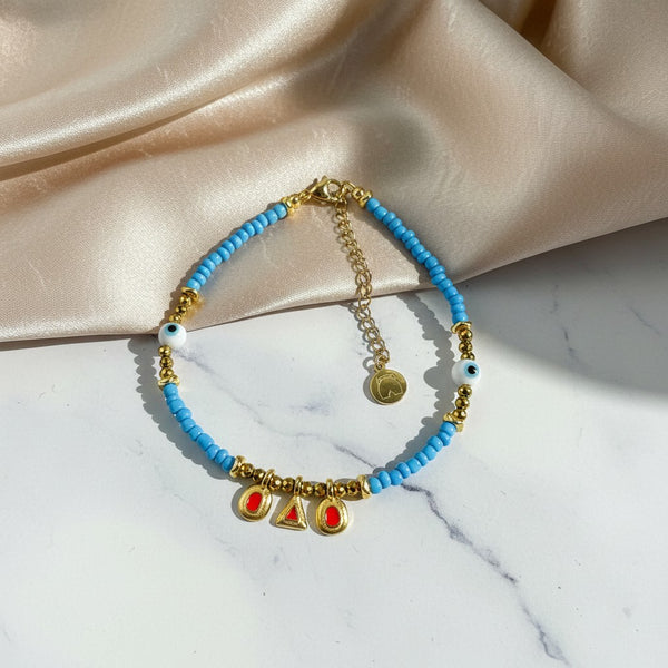 Elephantina.gr boho ankle bracelet with blue beads, gold accents, hematite, evil eye charms, and red enamel. Handmade.