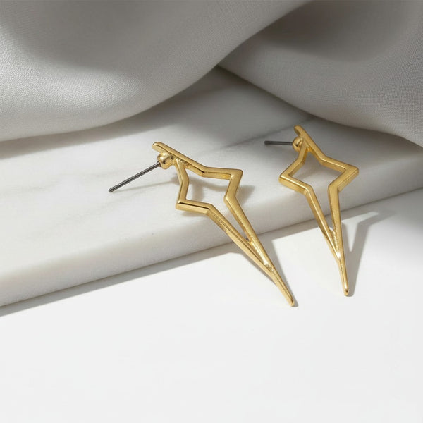 elephantina.gr gold-tone geometric starburst stud earrings with an open-frame design on a white marble surface.