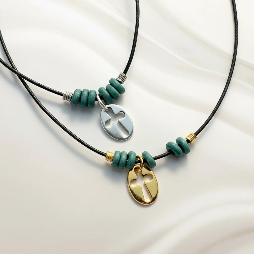 Handmade necklace with blue beads, black cord, and brass cross pendant by elephantina.gr. Available in silver and gold finishes.