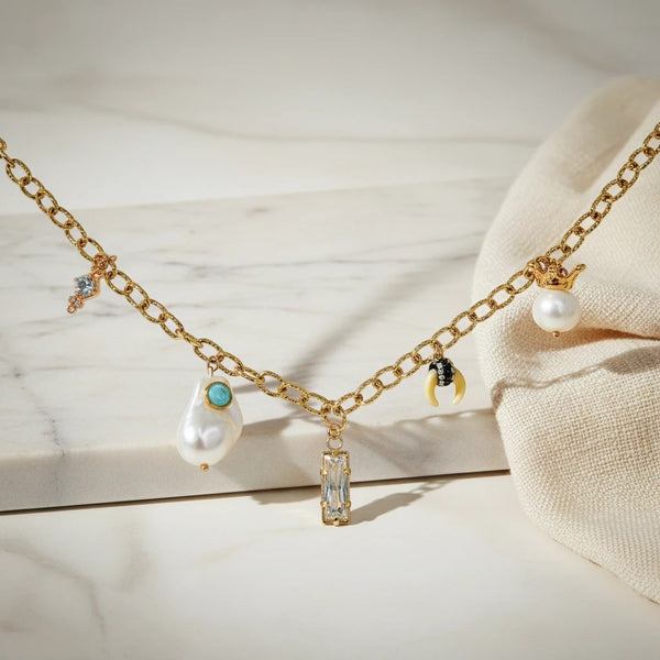 elephantina.gr gold chain necklace with baroque pearl, crystal, and unique charms like a strawberry and crown.