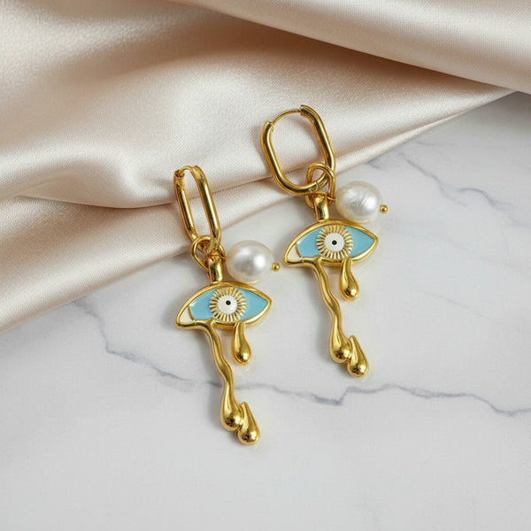 elephantina.gr gold hoop earrings with light blue evil eye charms, white pearls, and unique melting drop design.