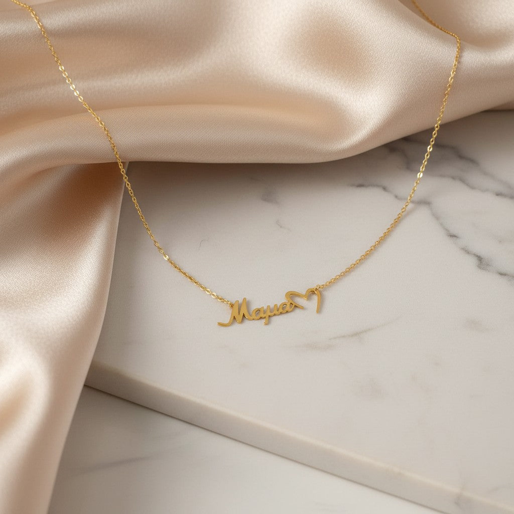 Gold-tone stainless steel necklace with "Mama" script and a cutout heart detail. Adjustable chain.