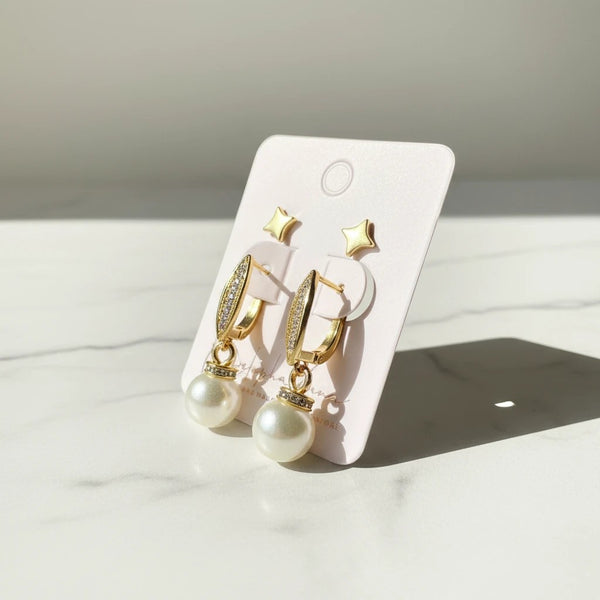 Elegant pearl drop earrings with cubic zirconia hoops and matching star studs, gold-tone.