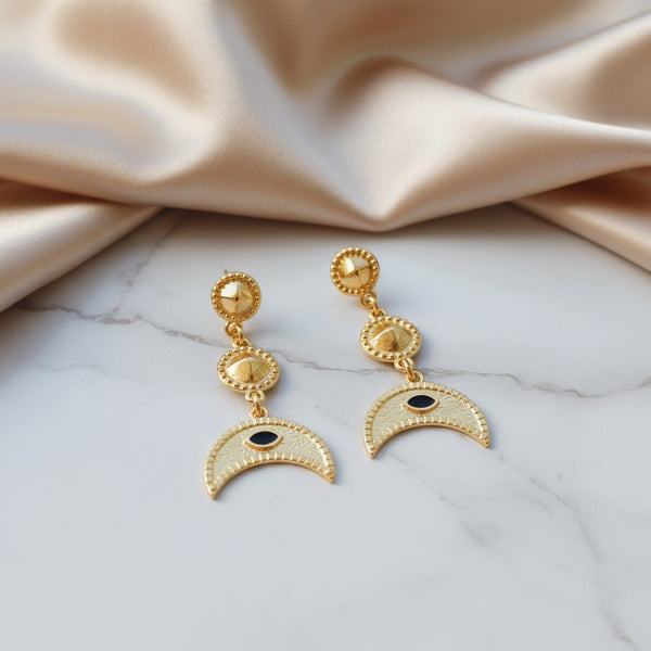 elephantina.gr 24k gold-plated brass dangle earrings featuring a crescent moon and enamel evil eye charm.